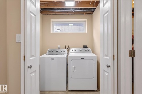 Dedicated laundry area with a white top-load washer and dryer set, neutral wall paint, a rectangular window, and exposed ceiling joists - 1904 36 Avenue, Edmonton, AB - Indoor Photo Showing Laundry Room