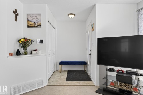 Entryway featuring a white front door with a frosted glass insert, neutral-toned flooring, and a built-in closet with bi-fold doors - 1904 36 Avenue, Edmonton, AB - Indoor Photo Showing Other Room