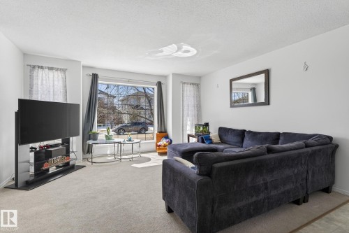 Bright living area featuring a large picture window, neutral wall paint, and light-colored carpeting - 1904 36 Avenue, Edmonton, AB - Indoor Photo Showing Living Room
