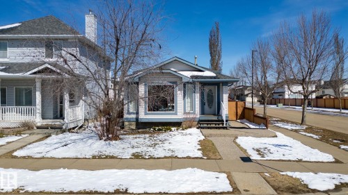 Ranch-style residence featuring light-colored siding, a dark roof, and a prominent front entrance with a decorative glass door - 1904 36 Avenue, Edmonton, AB - Outdoor