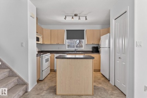 Kitchen featuring light wood-finish cabinetry, dark countertops, and essential white appliances - 1904 36 Avenue, Edmonton, AB - Indoor Photo Showing Kitchen With Double Sink