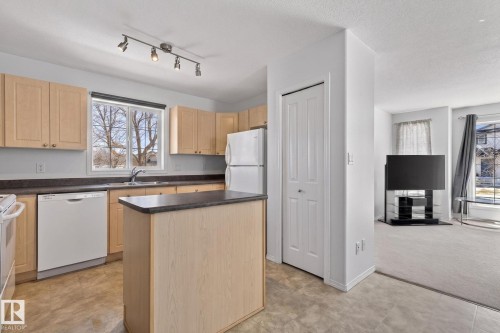 Kitchen featuring light wood-finish cabinetry, a central island with a dark countertop, and track lighting - 1904 36 Avenue, Edmonton, AB - Indoor Photo Showing Kitchen With Double Sink