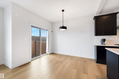 Open-concept living space featuring wood-finish flooring, a modern black pendant light, and crisp white walls - 3193 Checknita Way, Edmonton, AB - Indoor Photo Showing Kitchen