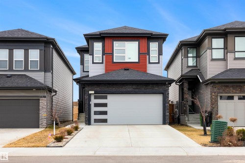 Contemporary exterior featuring a stone and siding facade, a modern garage door with frosted inserts, and a paved driveway - 3193 Checknita Way, Edmonton, AB - Outdoor With Facade