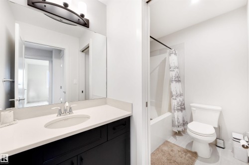 Bathroom featuring a dark wood-finish vanity with an undermount sink, light-toned countertop, and chrome fixtures - 3193 Checknita Way, Edmonton, AB - Indoor Photo Showing Bathroom