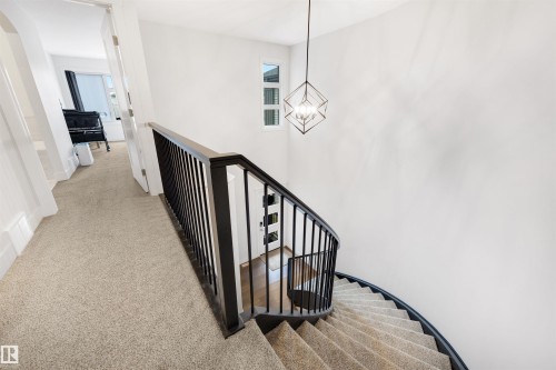 Curved staircase with black metal balusters and wood-finish railing - 3193 Checknita Way, Edmonton, AB - Indoor Photo Showing Other Room
