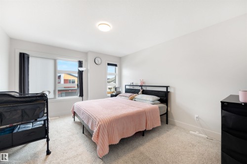Bright room featuring two windows with dark curtains, light-colored carpeting, white walls, and a flush mount ceiling light - 3193 Checknita Way, Edmonton, AB - Indoor Photo Showing Bedroom