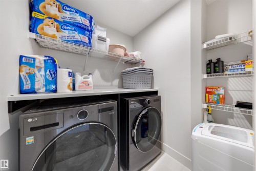 Dedicated laundry area featuring a front-load washer and dryer, white wire shelving, a built-in countertop, and neutral wall finishes - 3193 Checknita Way, Edmonton, AB - Indoor Photo Showing Laundry Room