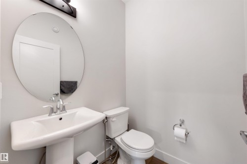 Pedestal sink with chrome fixtures and an oval mirror - 3193 Checknita Way, Edmonton, AB - Indoor Photo Showing Bathroom