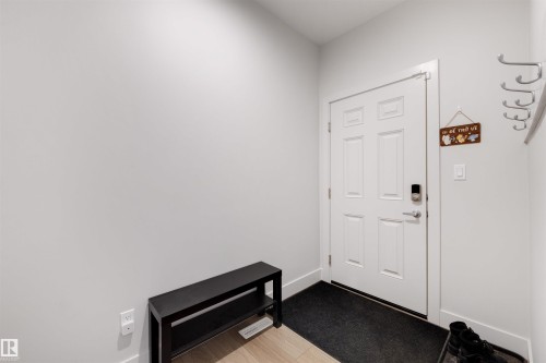 Entryway featuring a paneled door with smart lock hardware, light-toned walls, and wood-finish flooring - 3193 Checknita Way, Edmonton, AB - Indoor Photo Showing Other Room
