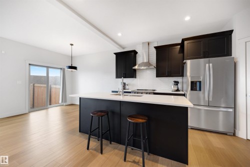 Kitchen featuring dark cabinetry, white subway tile backsplash, stainless steel appliances, and a central island with a white countertop - 3193 Checknita Way, Edmonton, AB - Indoor Photo Showing Kitchen With Stainless Steel Kitchen With Upgraded Kitchen