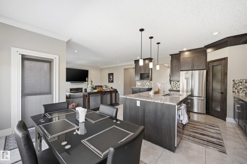 The kitchen features an island with a sink, pendant lighting, and stainless steel appliances - 2018 Armitage Green, Edmonton, AB - Indoor Photo Showing Other Room