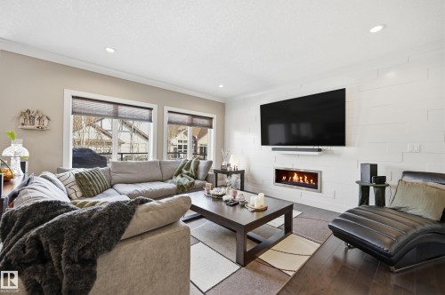 Living room featuring dark hardwood floors, a contemporary fireplace, and recessed lighting - 2018 Armitage Green, Edmonton, AB - Indoor Photo Showing Living Room With Fireplace