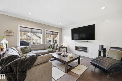 Living room with hardwood floors, a modern fireplace, and recessed lighting - 2018 Armitage Green, Edmonton, AB - Indoor Photo Showing Living Room With Fireplace