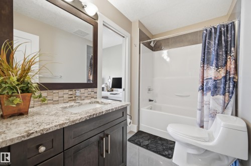 This bathroom features a contemporary vanity with a granite countertop, an undermount sink, and a large mirror - 2018 Armitage Green, Edmonton, AB - Indoor Photo Showing Bathroom