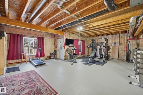 Spacious room with exposed wood ceiling beams, a window with views of outdoor greenery, and a white door with a window - 2018 Armitage Green, Edmonton, AB - Indoor