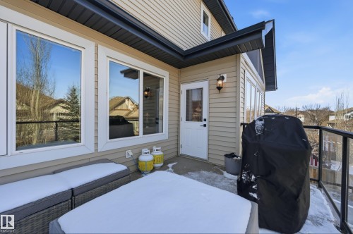 The property features a balcony with glass railings, a white door providing exterior access, and beige siding - 2018 Armitage Green, Edmonton, AB - Outdoor With Exterior