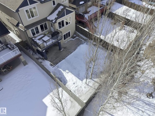 The property features a two-story exterior with light-colored siding and a dark roof, a raised deck with a glass railing, and a fenced yard - 2018 Armitage Green, Edmonton, AB - Outdoor