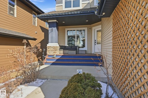 The property features a front porch with blue steps, a white entry door with decorative glass, and a stone-clad column - 2018 Armitage Green, Edmonton, AB - Outdoor