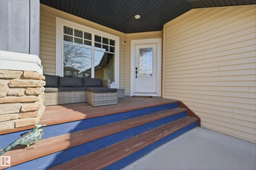 Inviting front porch with a wood deck, blue risers, and a stone pillar accent - 2018 Armitage Green, Edmonton, AB - Outdoor With Deck Patio Veranda With Exterior
