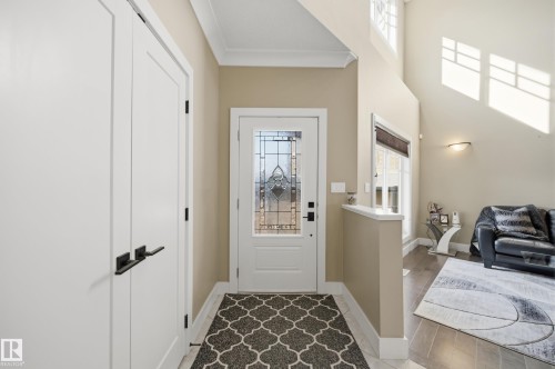 The property features a welcoming entryway with a decorative glass front door, two white doors with black hardware, and a high ceiling - 2018 Armitage Green, Edmonton, AB - Indoor Photo Showing Other Room