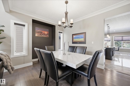 A dining area featuring hardwood floors, crown molding, and a chandelier with five lights - 2018 Armitage Green, Edmonton, AB - Indoor Photo Showing Dining Room