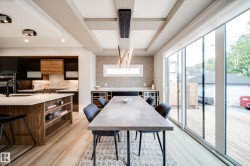 Open concept dining area with light wood-finish flooring, featuring a large concrete-finish dining table and a contemporary linear light fixture - 