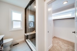 Glass-enclosed shower featuring a built-in bench, dark tile surround, and matte black hardware - 
