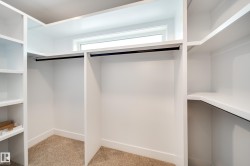 Built-in closet system featuring white shelving, hanging rods, and a window - 