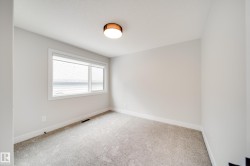 Neutral-toned room featuring a large window, light gray carpeting, and white baseboards - 