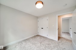Room featuring light gray wall paint, gray carpet flooring, white trim, and a contemporary ceiling light fixture with a wood-finish base - 