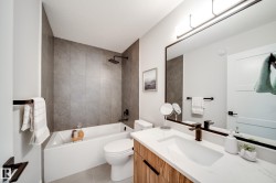 Full bathroom featuring a rectangular bathtub, large format stone-look wall tiling, and a black rain shower head - 