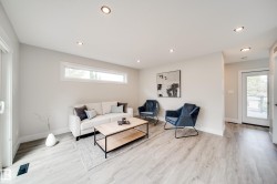 Bright living area featuring wood-finish flooring, recessed ceiling lighting, a long horizontal window, a glass-paned door, and white trim throughout - 