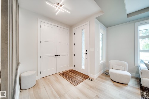 Bright entryway featuring light wood-finish flooring and a contemporary linear ceiling light fixture - 9625 101 Street, Edmonton, AB - Indoor Photo Showing Other Room