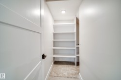 Recessed lighting illuminates extensive built-in shelving, complemented by white walls and a light-toned carpeted floor - 