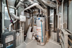 Utility room featuring a water heater, multiple HVAC units, and extensive ductwork - 
