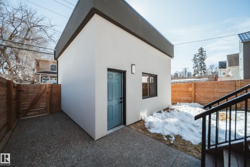 Modern auxiliary structure featuring a light blue entry door, black window frame, exterior wall lighting, and a flat roofline - 9625 101 Street, Edmonton, AB - Outdoor With Exterior