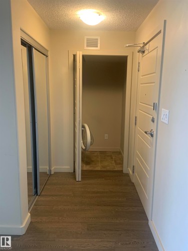 Entryway featuring wood-finish flooring, a flush-mount ceiling light, and a built-in closet with mirrored sliding doors - 307 6084 Stanton Drive, Edmonton, AB - Indoor Photo Showing Other Room
