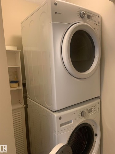 Stacked white front-loading washer and dryer units - 307 6084 Stanton Drive, Edmonton, AB - Indoor Photo Showing Laundry Room