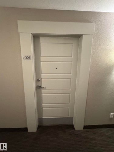 White panel door with satin nickel hardware and a contemporary door frame - 307 6084 Stanton Drive, Edmonton, AB - Indoor Photo Showing Other Room