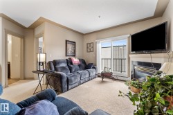 The living room features carpeted flooring, a fireplace with a dark tile surround and white mantel, and a sliding glass door providing natural light and access to a balcony - 