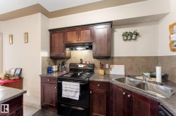 The property features a kitchen with dark wood cabinetry, a black electric range, and a double basin stainless steel sink - 