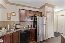 The kitchen features wooden cabinetry, a double basin sink, and a stainless steel refrigerator - 