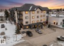 The property is a multi-story building featuring an entrance canopy with stone accents and a paved parking lot - #211 4415 48 St, Leduc, AB  - Outdoor 