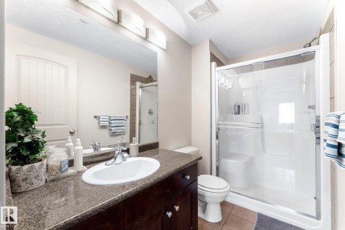 Well-appointed bathroom featuring a vanity with a large mirror and overhead lighting, a shower with a sliding glass door, and tiled flooring - #211 4415 48 St, Leduc, AB - Indoor Photo Showing Bathroom
