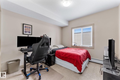 This room features a window with horizontal blinds, neutral wall tones, and carpeted flooring - #211 4415 48 St, Leduc, AB - Indoor Photo Showing Bedroom
