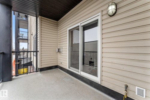 The property features a private balcony with a concrete floor, black metal railings, and a sliding glass door for access - #211 4415 48 St, Leduc, AB - Outdoor With Exterior