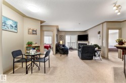 This inviting living space features light-colored carpeting throughout and a fireplace with a mantel - 