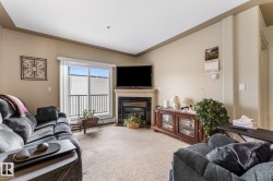 Living area featuring a fireplace with a black surround, light-colored carpeting, and a sliding glass door providing natural light and access to an outdoor space with a black railing - 