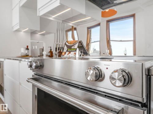 The kitchen features modern white cabinetry, a stainless steel range with an oven, and a contemporary faucet - 807 10134 100 Street, Edmonton, AB - Indoor Photo Showing Kitchen
